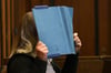Die Angeklagte deckt im Landgericht ihr Gesicht mit einem blauen Ordner ab. Rund acht Monate nach der Entdeckung eines getöteten Babys in Mönchengladbach beginnt der Prozess gegen die Mutter des Kindes.