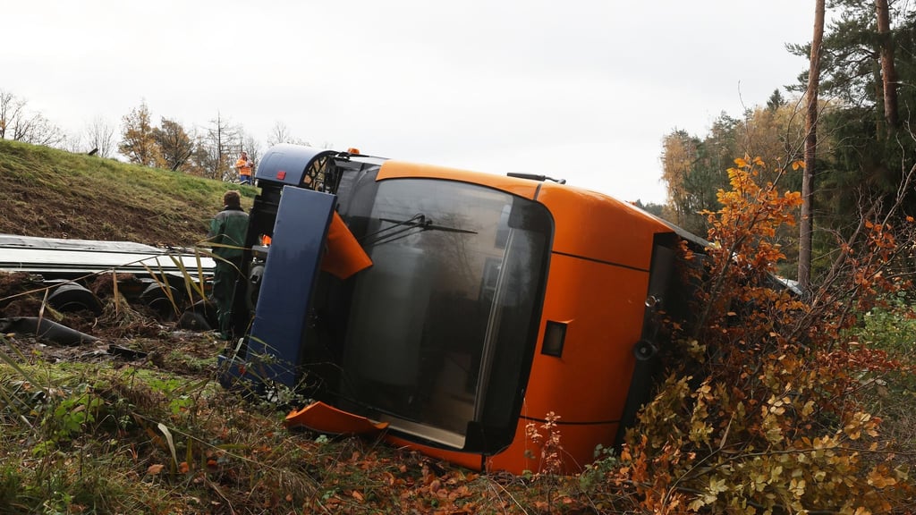 Ein Schwerlasttransporter und ein Straßenbahnwagen liegen unterhalb der Autobahn 9 in einem Graben.
