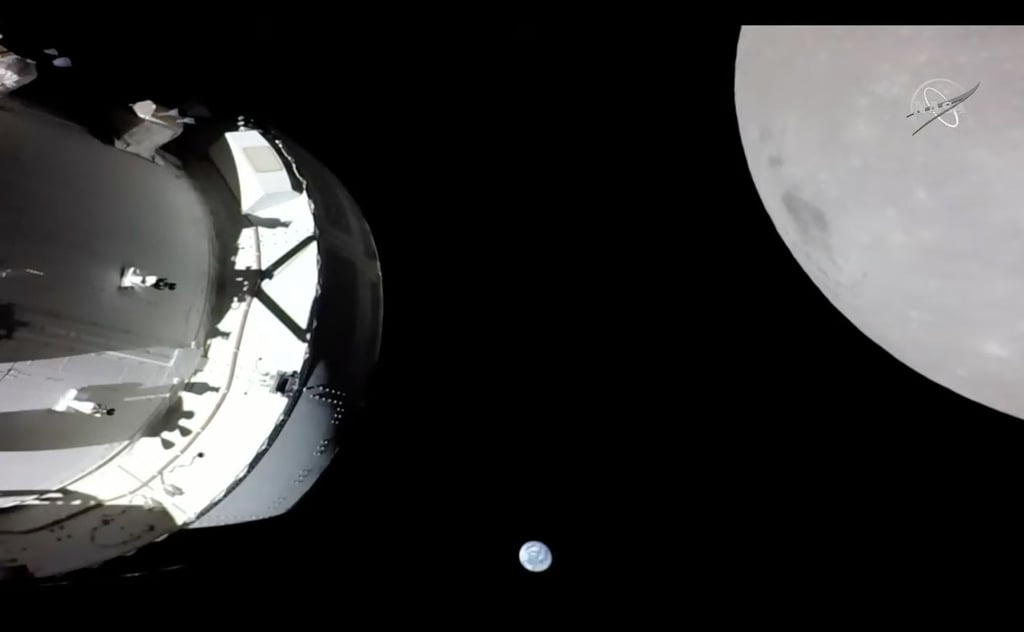 Eine Kamera an Bord der „Orion“-Kapsel zeigt das Raumschiff (l) im Weltraum, den Mond (r) und klein im Hintergrund die Erde.