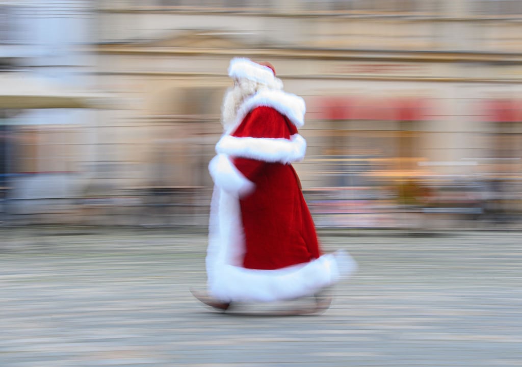 Ein Weihnachtsmann läuft über einen Marktplatz.