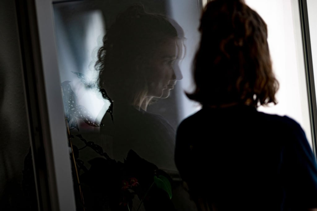 Eine frau steht im geöffneten Fenster einer Wohnung.