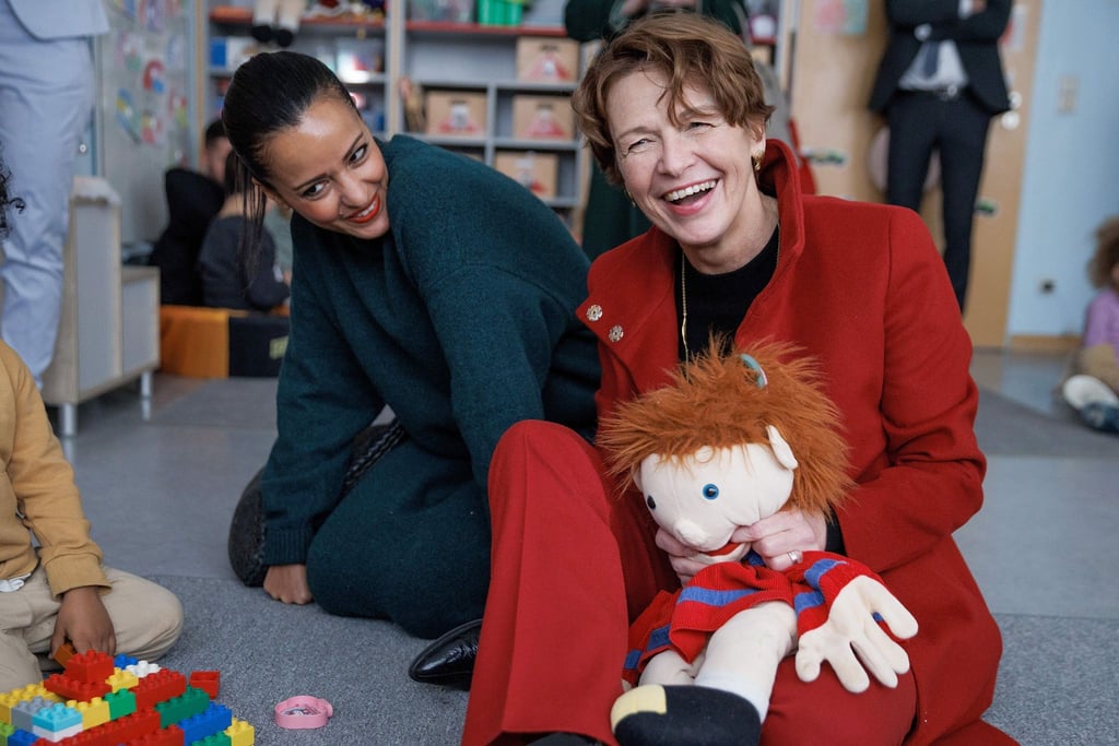 Elke Büdenbender, Ehefrau des Bundespräsidenten, sitzt gemeinsam mit Sawsan Chebli (l.,SPD). bei einem Besuch einer Kita auf dem Boden.