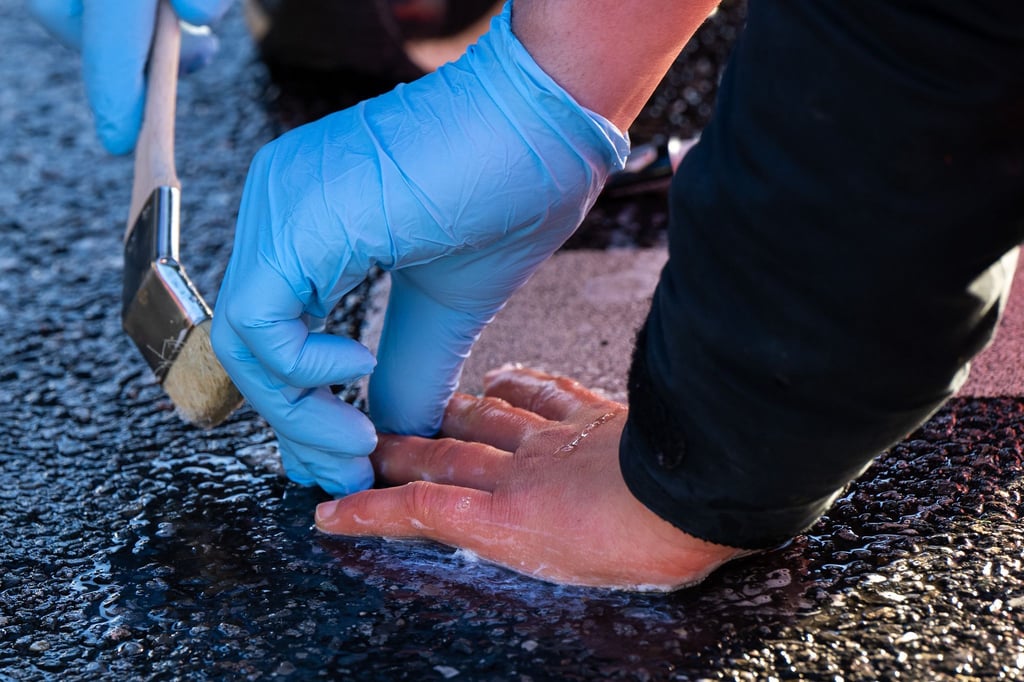 Ein Polizisten löst die Verklebung, mit der sich ein Klimaaktivist der Umweltschutzbewegung „Letzte Generation“ geklebt hatte.