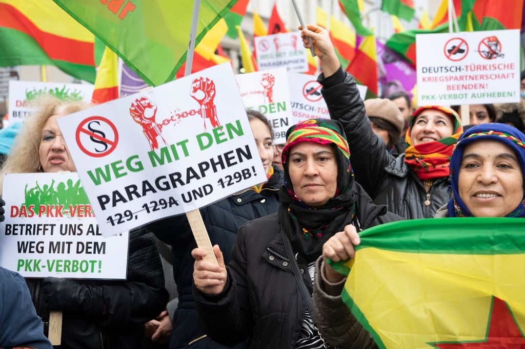 Teilnehmerinnen stehen am Hermannplatz und halten Fahnen und Schilder .