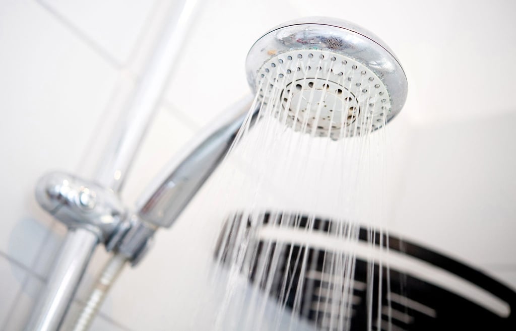 Ein Duschkopf hängt in einer Dusche in einem Badezimmer.