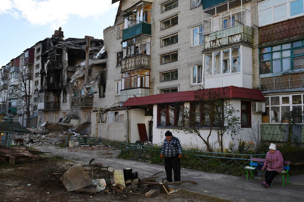 In der ukrainischen Stadt Swjatohirsk bereitet ein Mann eine Mahlzeit neben einem durch Beschuss beschädigten Wohnhaus zu.
