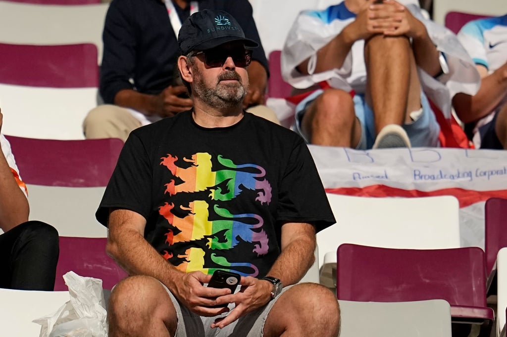 Ein Fan mit einem Regenbogen-Shirt sitzt auf der Tribüne.