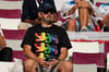Ein Fan mit einem Regenbogen-Shirt sitzt auf der Tribüne.