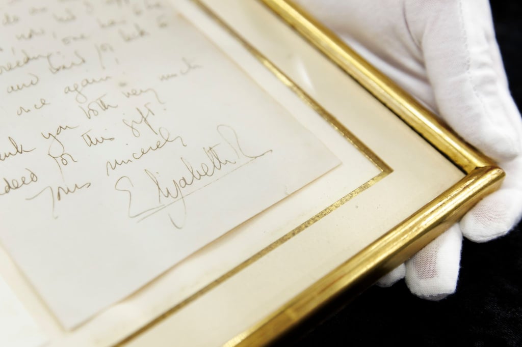 Ein handgeschriebener Brief von Königin Elizabeth II. (1926-2022) aus dem Jahr 1966 wird versteigert. Die Unterschrift der Queen ist auf einer Kopie der Rückseite zu sehen, welche dem eingerahmten Brief beiliegt.