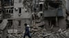 Eine Frau geht an den Trümmern eines zerstörten Hauses nach einem Luftangriff vorbei.