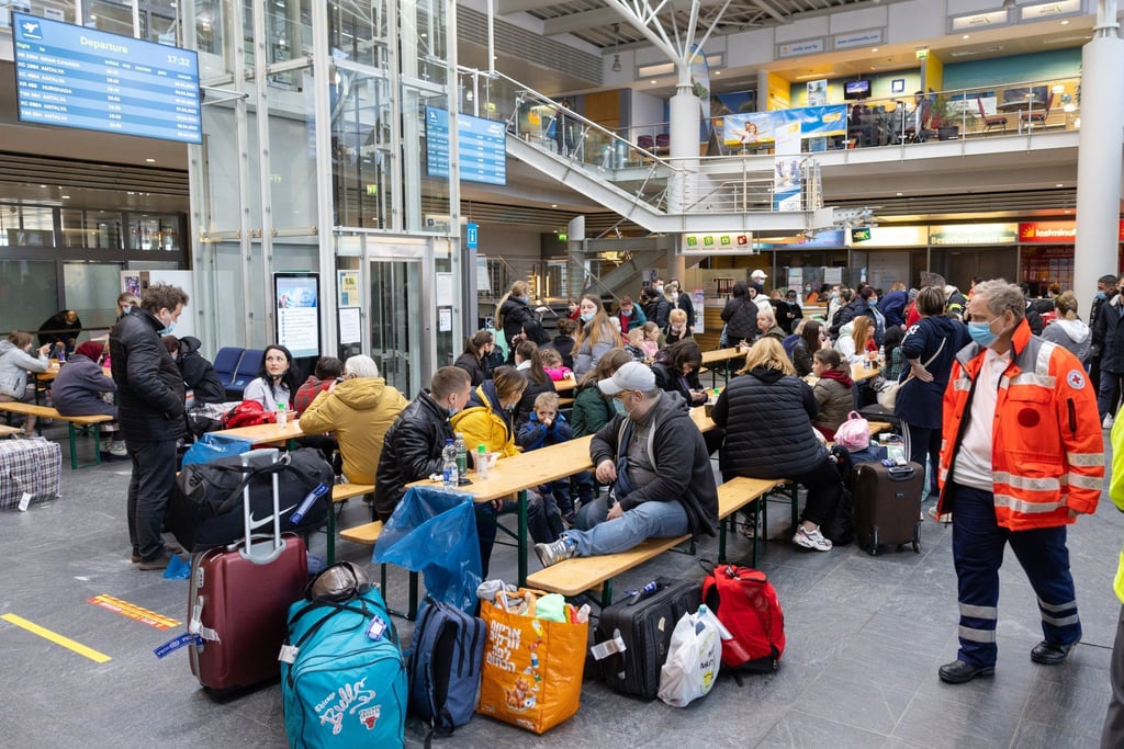 Geflüchtete aus der Ukraine sitzen nach der Ankunft im Flughafen Erfurt-Weimar und werden von Helfern betreut.