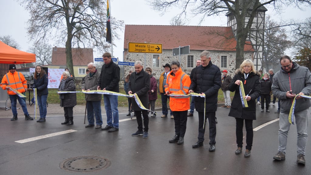 Michael Thiesing von der Strabag (von rechts), Meike Portius und Hans-Heinrich Röhrs von der Landesstraßenbaubehörde, der stellvertretende Landrat Matthias Baumann, Ortsbürgermeister Christian Henneick, die beiden Breitenfelder Wolfgang Flögel und Elfriede Henneick sowie Stefanie Sutter vom städtischen Bauamt gaben mit einem Scherenschnitt die Straße offiziell frei.