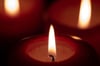 Drei Kerzen brennen in einem dunklen Raum.