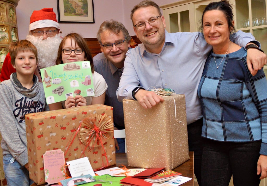 Der Weihnachtsmann hat die Wünsche und Lukas und Kyra von der „Arche“ fest im Blick. Heimleiter Titus Linke (4.v. li.) freut sich über die „Weihnachtswichtel-Aktion“ der Werbegemeinschaft. Stefan B. Westphal und Verena Schiffner organisieren und koordinieren die Spendensammlung.