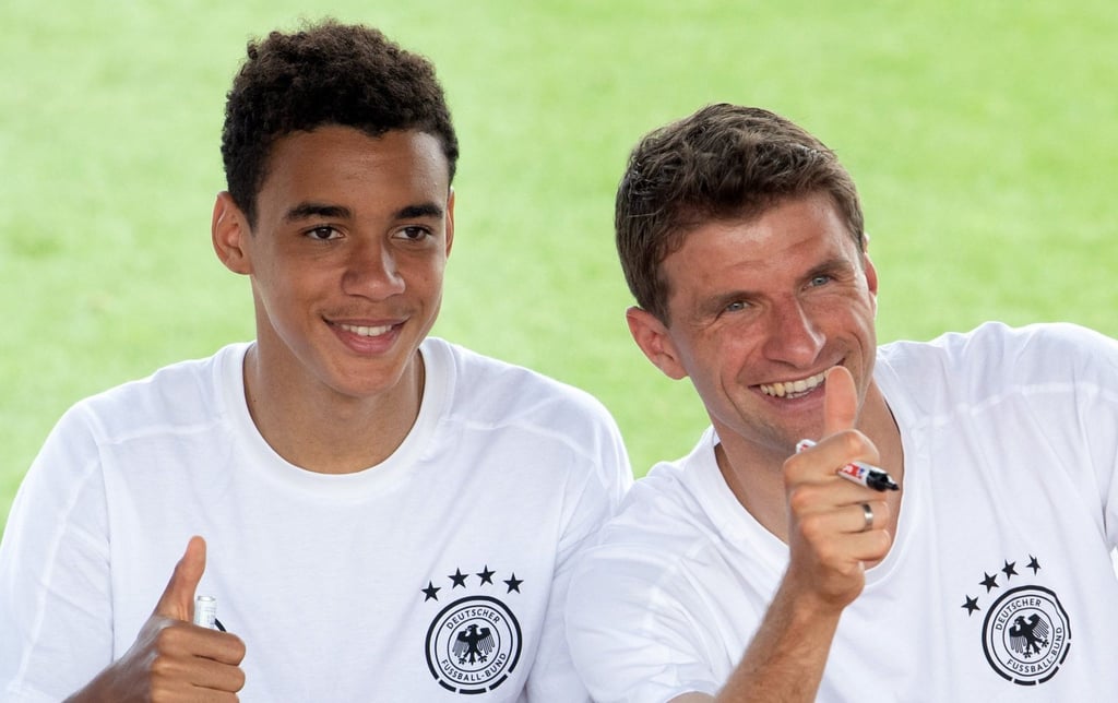 Deutschlands Jamal Musiala (l) und Thomas Müller grüßen Fans während einer Autogrammstunde.