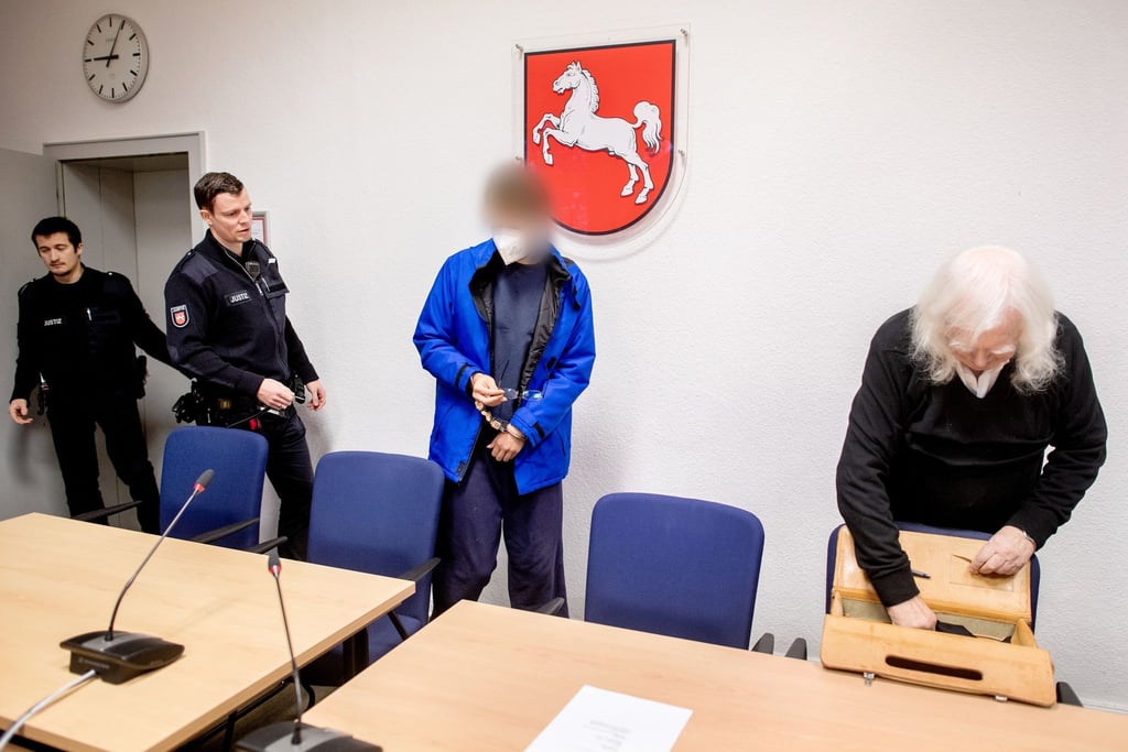Der Angeklagte wird vor Prozessbeginn in einen Gerichtssaal im Landgericht zu seinem Anwalt (r) geführt.