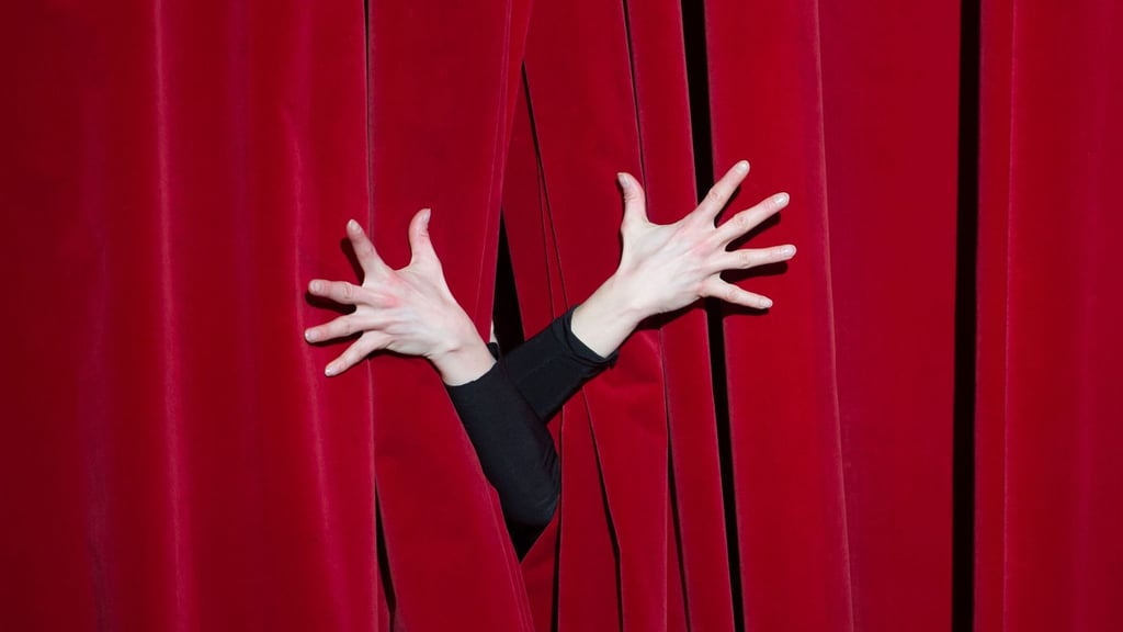 Hände einer Schauspielerin sind während der Fotoprobe für ein Ballettstück auf dem Vorhang zu sehen.