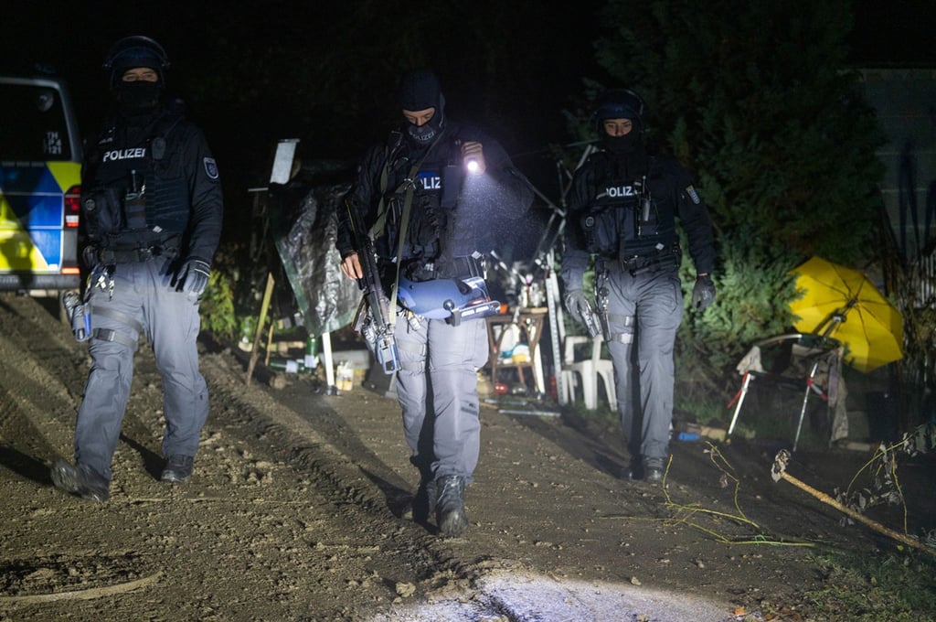 Polizisten suchen nach Waffen und Sprengstoff auf dem Grundstück eines Mannes.