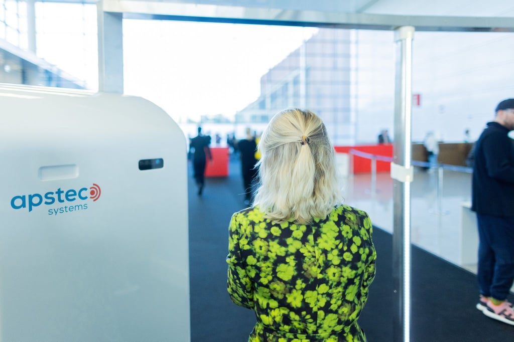 Besucher der Art Cologne gehen am Eingang zu einer Messehalle der Kunstmesse Art Cologne durch eine Sicherheitskontrolle mit Körperscannern.
