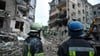 Rettungskräfte im ukrainischen Saporischschja schauen auf die Trümmer eines zerstörten Wohnhauses.