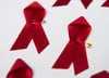 Viele rote Schleifen, das weltweit anerkannte Symbol für die Solidarität mit HIV-Infizierten, liegen auf einem Tisch.