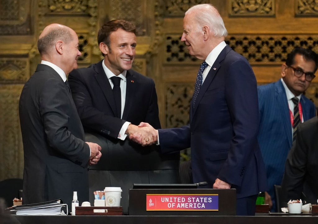 US-Präsident Joe Biden (r) und Frankreichs Präsident Emmanuel Macron begrüßen sich während des G20-Gipfels in Indonesien, daneben steht Bundeskanzler Olaf Scholz.