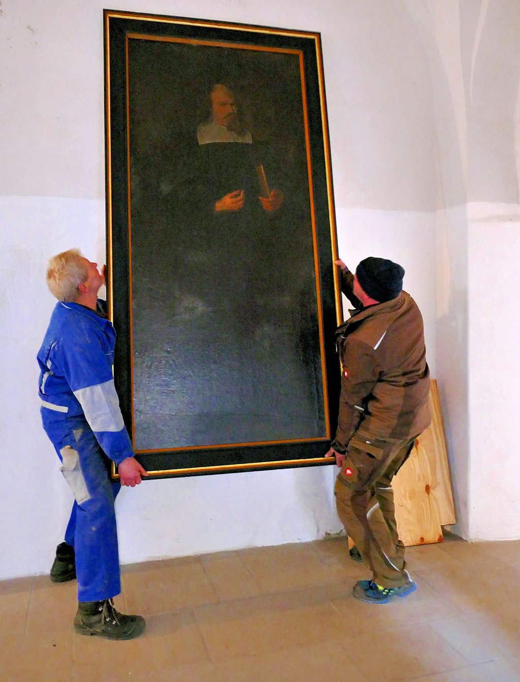 Eckhard Ludwig und Matthias Döring hängen das Gemälde ab, das unter den Mitarbeitern der Lichtenburg als „Pastor Schlaf“ bekannt ist.
