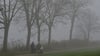 Spaziergänger sind bei dichtem Nebel unterwegs.