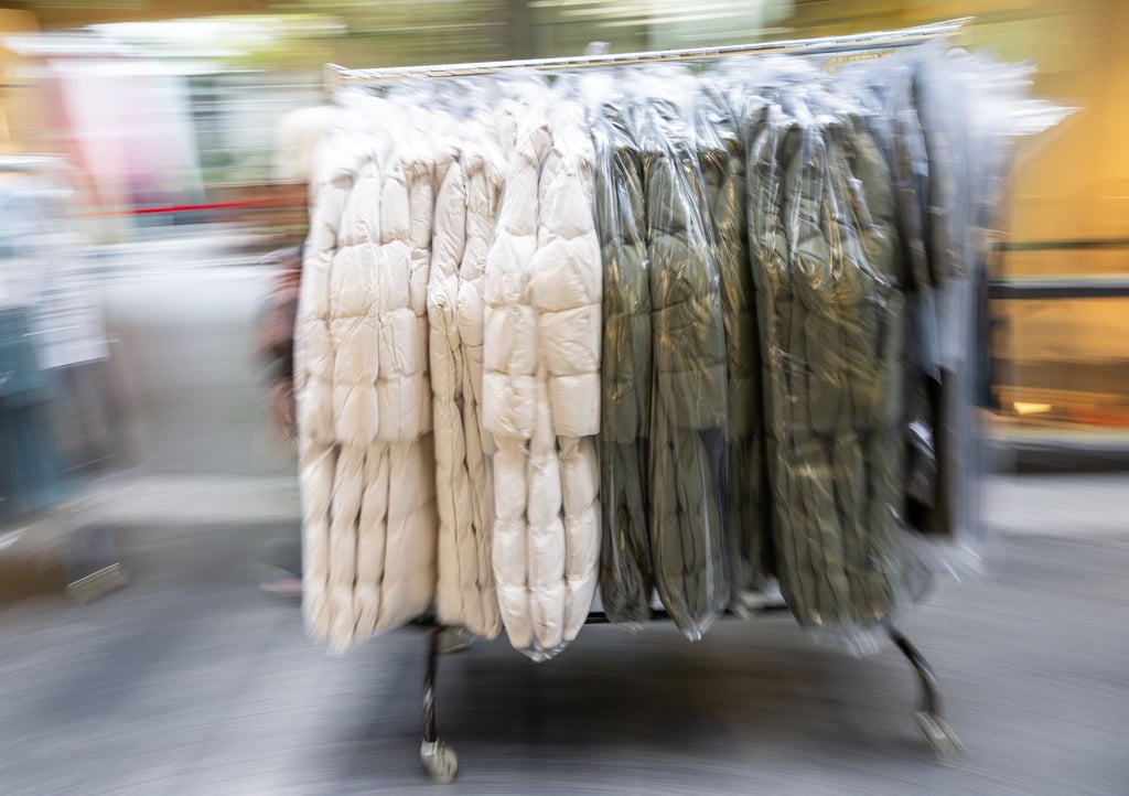 Wintermäntel auf einer Transportvorrichtung werden in der Münchner Fußgängerzone aus dem Lager zu einem Bekleidungsgeschäft gefahren.
