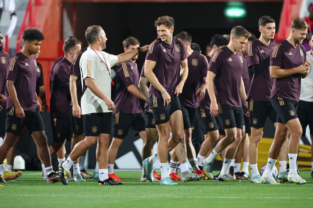 Bundestrainer Hansi Flick (2vl) und Leon Goretzka (M) scherzen während einer Trainingseinheit.
