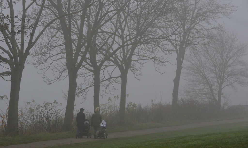 Spaziergänger sind bei dichtem Nebel unterwegs.