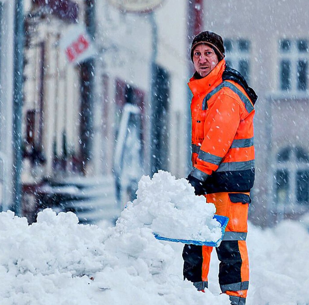 Lars Kissmann vom städtischen Winterdienst schippt Schnee auf dem Neumarkt von Zeitz.