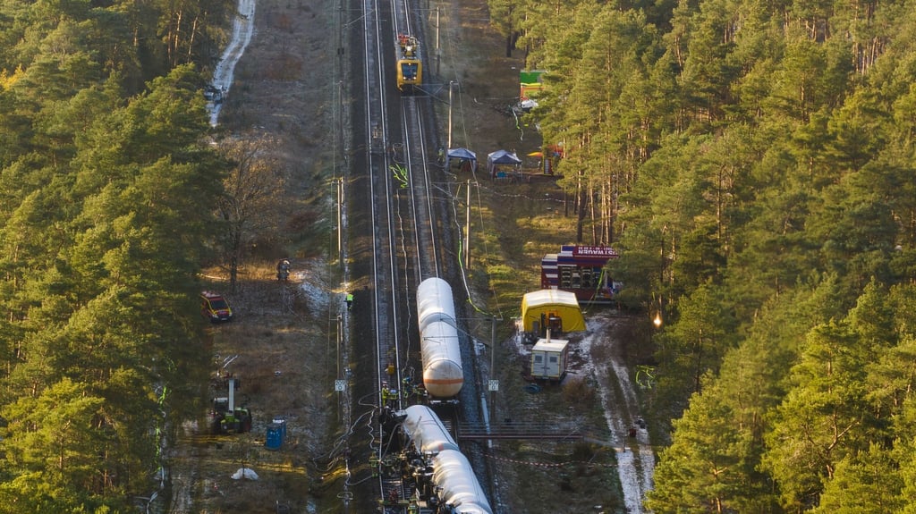 Beschädigte Waggons stehen und liegen auf dem Bahndamm.