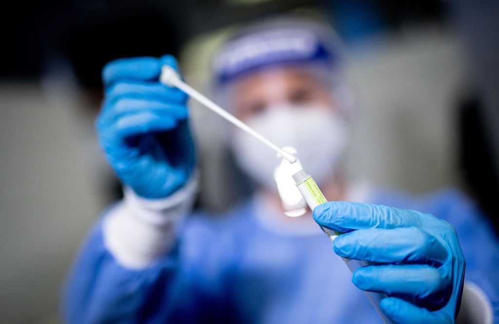 Eine medizinische Mitarbeiterin hält in einem Corona-Testzentrum ein Abstrichstäbchen in der Hand.