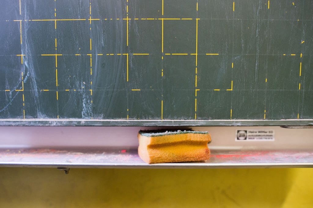 Ein Schwamm liegt in einem Klassenzimmer vor einer Tafel.