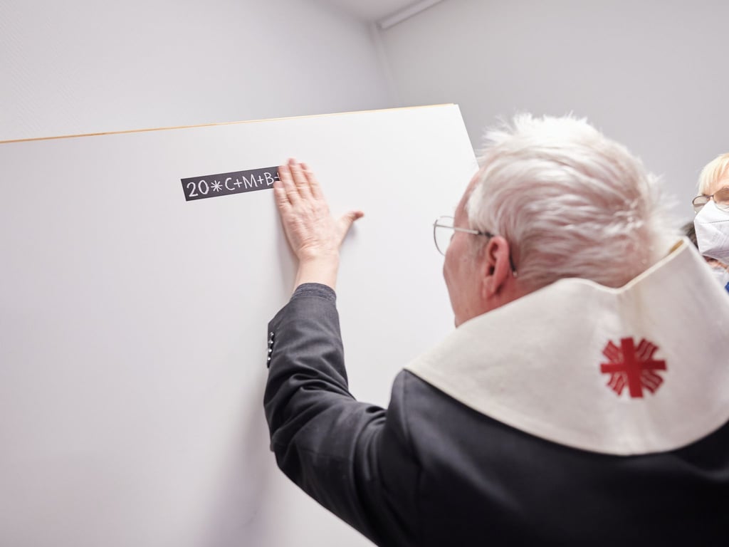 Stefan Dybowski, Prälat klebt im Caritas-Hospiz-Zentrum die Buchstaben C+M+B an die Tür, nachdem er den Raum gesegnet hat.