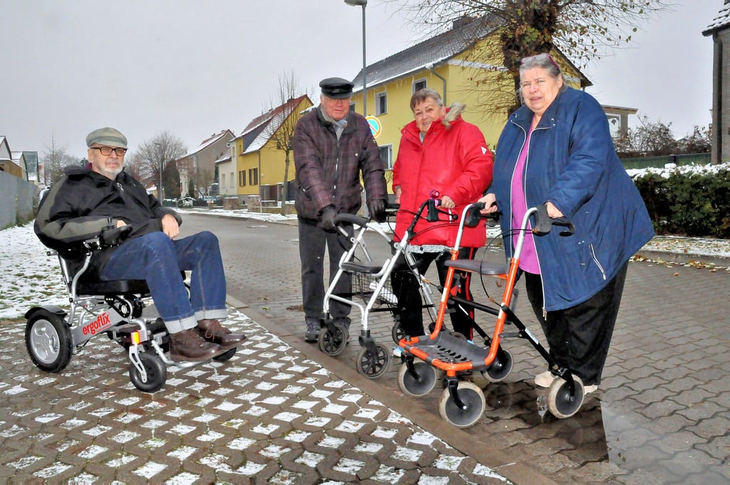 Heiner Güssow, Klaus-Dieter Bauer, Jutta Zorn und Sigrid Güssow an der Barriere, die ihnen so zu schaffen macht: der nicht abgesenkte Bordstein an der Einfahrt zu ihrer ansonsten barrierefreien Wohnsiedlung.