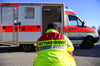 „Rettungsdienst“ steht auf der Jacke eines Mannes vor einem Rettungswagen der Feuerwehr.