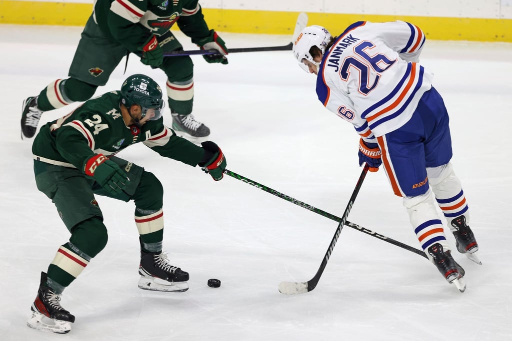 Matt Dumba (24) von Minnesota Wild und Mattias Janmark (26) von den Edmonton Oilers jagen nach dem Puck.