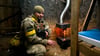 Ein ukrainischer Soldat wärmt sich an einem Ofen.