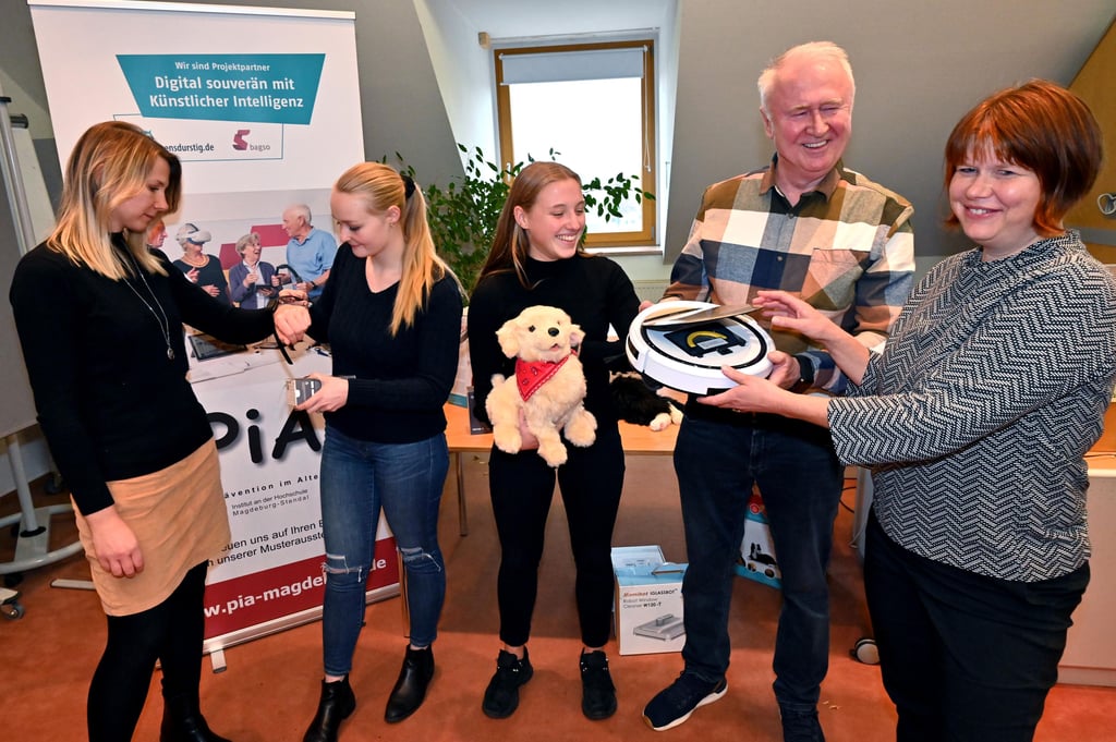 Wie können smarte Geräte und kleine Roboter Senioren im Alltag helfen? Ein Projekt bringt den Praxistest. Hier Anna Heitzmann (PiA) und die Studentinnen Jasmina Werner (mit Smartwatch) und Ella Hofer (Roboterhund), Dr. Manfred Peter (mit Staubsaug-Roboter) sowie Prof. Carolin Kollewe.