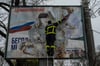 Ein ukrainischer Feuerwehrmann reißt in der kürzlich befreiten Stadt Cherson ein russisches Werbeplakat von einer Werbetafel.