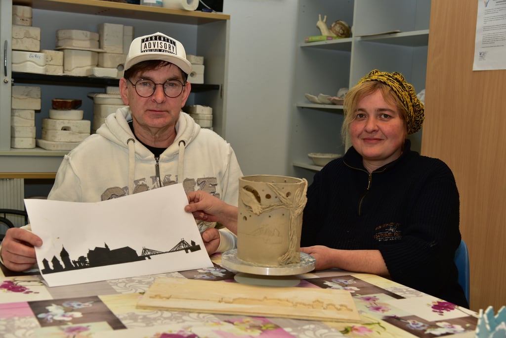 Alice Jahn und Michael Bunge präsentieren das Windlicht, auf dem neben der typischen Krähe auch die Skyline von Nienburg abgebildet ist.