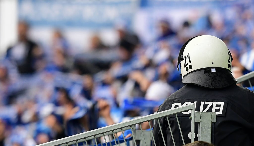 Ein Polizist mit Helm vor 1. FC Magdeburg-Fans - kein seltener Anblick.