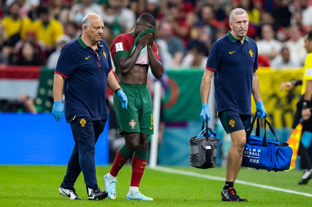 Portugals Nuno Mendes (M) wird verletzt vom Platz geleitet.