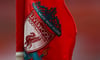 Das Wappen von FC Liverpool mit der Aufschrift „You'll Never Walk Alone“ ist auf einer Fahne im Anfield zu sehen.