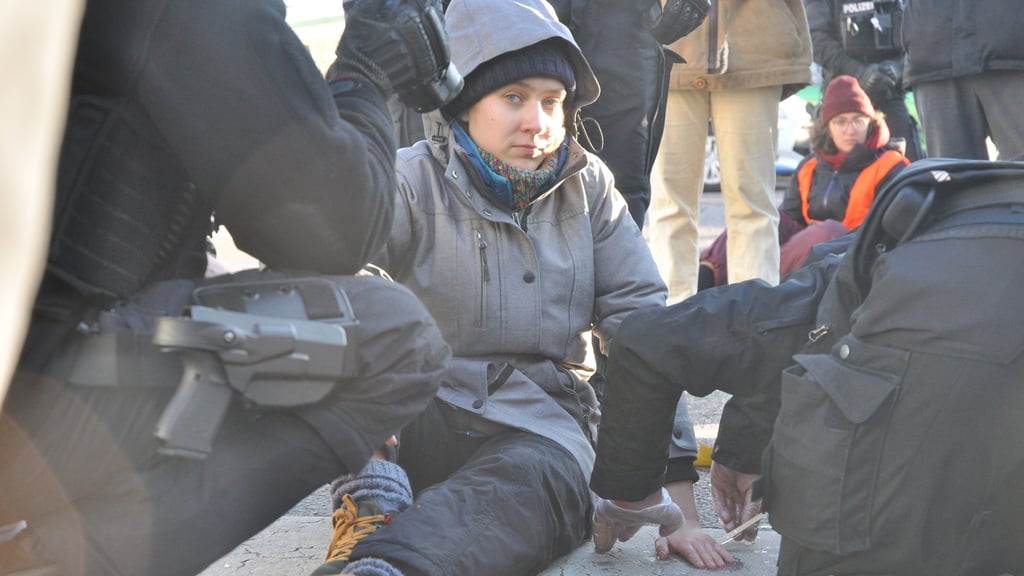 Polizisten lösen am 21. November 2022 die festgeklebte Hand der Leipziger Studentin Lina Schinköthe von der Walther-Rathenau-Straße in Magdeburg ab.