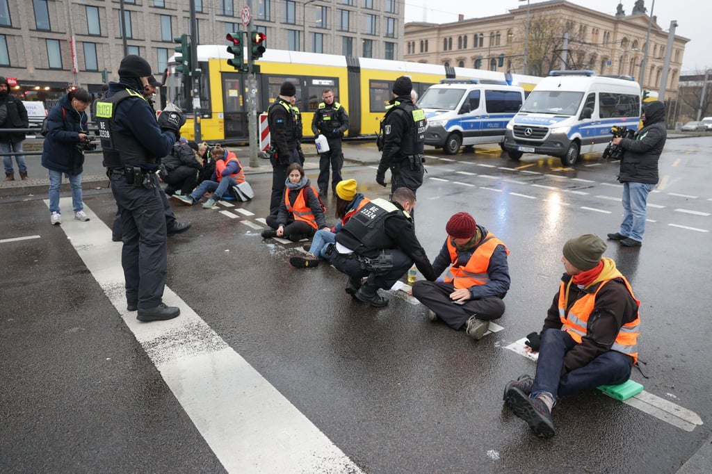 Polizisten lösen die Hand eines Klimaaktivisten vom Asphalt auf der Invalidenstraße.