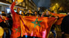 Marokko-Fans feiern auf der Straße mit Flaggen und Trommeln nach dem Sieg ihrer Mannschaft im Elfmeterschießen.
