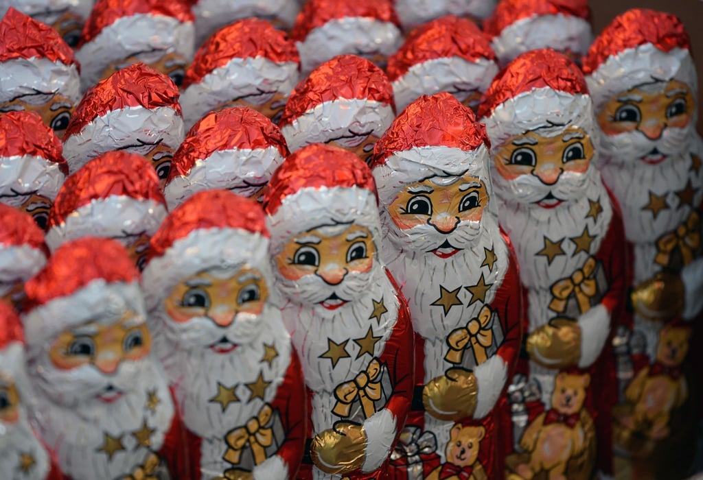 Schokoladenweihnachtsmänner stehen aufgereiht nebeneinander.